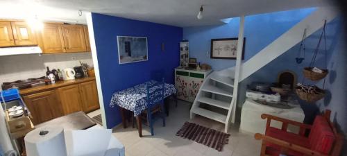 a kitchen with a blue wall and a table and a staircase at Pilion-Unique House at the Aegean Sea in Keramídhion