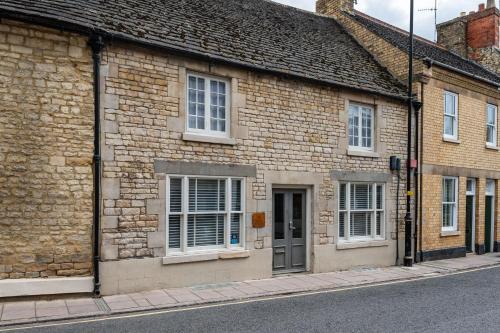 a brick building with white windows on a street at Stylish central 6 bedroom converted Granary in Stamford