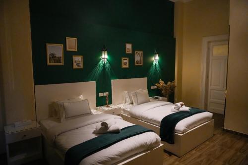 two beds in a room with green walls at Hathor House in Cairo