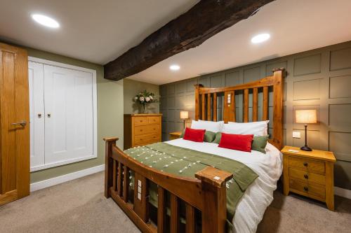 1 dormitorio con cama de madera y almohadas rojas en Stylish central 6 bedroom converted Granary, en Stamford