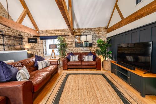 a living room with leather furniture and a flat screen tv at Stylish central 6 bedroom converted Granary in Stamford