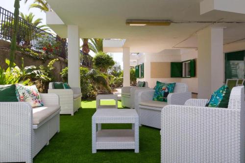 un patio con sedie di vimini bianche e tavoli in erba di PLAYA DEL INGLES-MASPALOMAS a Playa del Ingles