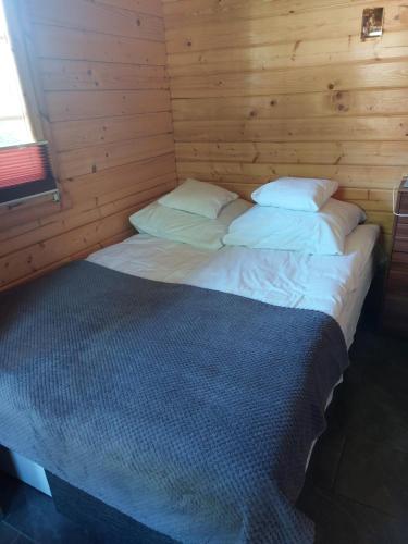 a large bed in a room with wooden walls at Letniskowy domek z Bali in Myszyniec