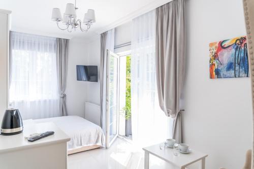 a white bedroom with a bed and a window at Fryderyk in Krynica Morska