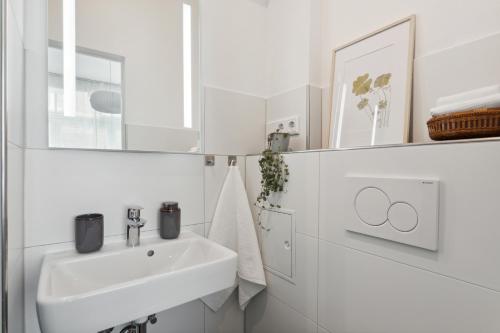 a white bathroom with a sink and a mirror at City Apartment! Bahnhof Kongress zentral ÖPNV in Kassel