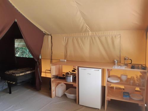 a tent with a refrigerator and a table in it at Camping Onlycamp Domelin in Beaufort