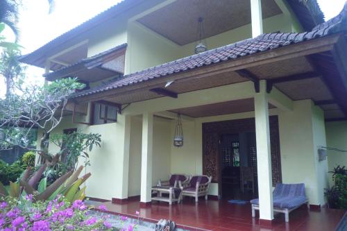 un porche de una casa con sillas y flores en Gerebig Bungalow, en Ubud