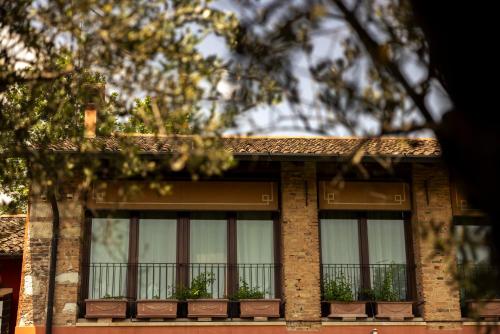 a brick building with three windows with plants on it at Musella Winery & Relais in San Martino Buon Albergo