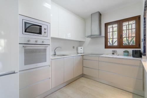 a white kitchen with white cabinets and a window at Casa en la playa con piscinas A in Puerto Marino