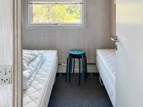 Fjellerup StrandにあるThree-Bedroom Holiday home in Glesborg 47のベッド2台、窓際のスツールが備わる客室です。
