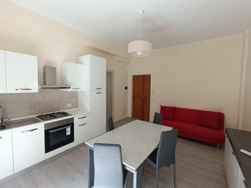 a kitchen with a table and a red couch at Lusitana Alloggi in Foligno