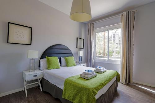 1 dormitorio con 1 cama con manta verde y ventana en Alcam Stadium Les Corts en Barcelona