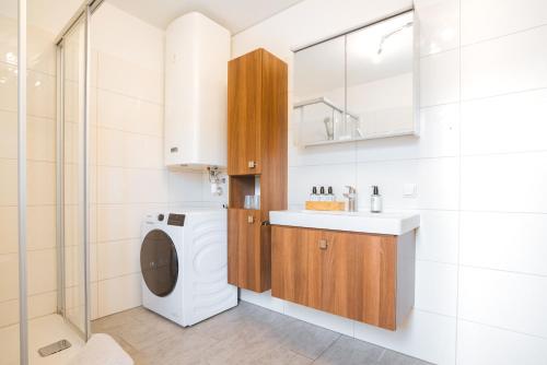 eine Waschküche mit einer Waschmaschine, einem Waschbecken und einer Waschmaschine in der Unterkunft Haus Bachinger in Mondsee