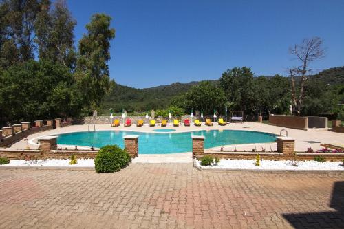 a large swimming pool with chairs in a park at Yeşilkaya Hotel in Kayakoy