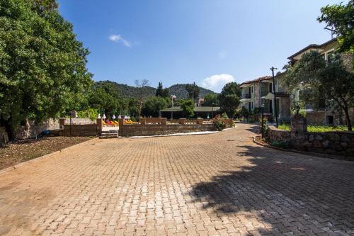 a cobblestone street in a town with houses and trees at Yeşilkaya Hotel in Kayakoy