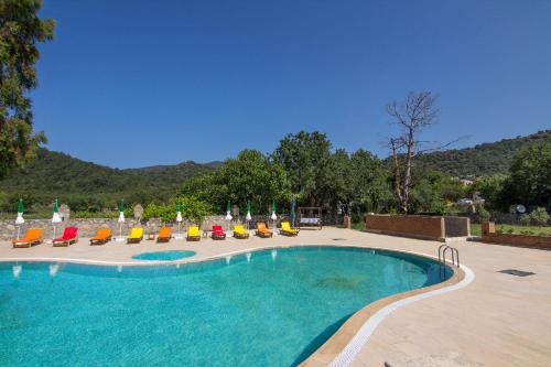 a large swimming pool with lounge chairs at Yeşilkaya Hotel in Kayakoy
