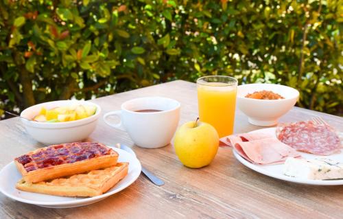 a table with breakfast foods and a glass of orange juice at ibis Budget Millau Viaduc in Millau