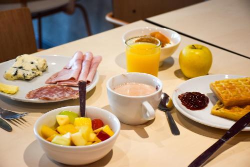a breakfast table with breakfast foods and a cup of orange juice at ibis Budget Millau Viaduc in Millau