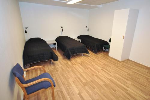 a room with three beds and a wooden floor at Brandbergens Vandrarhem in Haninge