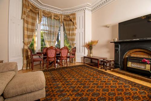 a living room with a fireplace and a table and chairs at Pass the Keys Traditional 5 Bed Bellahouston Glasgow Sleeps 10 in Glasgow