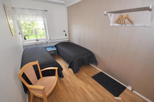 a bedroom with a bed and a chair and a window at Brandbergens Vandrarhem in Haninge