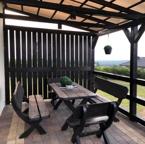 a wooden table and two chairs on a patio at Domek wypoczynkowy caloroczny w okolicach Zatora i Wadowic in Radocza