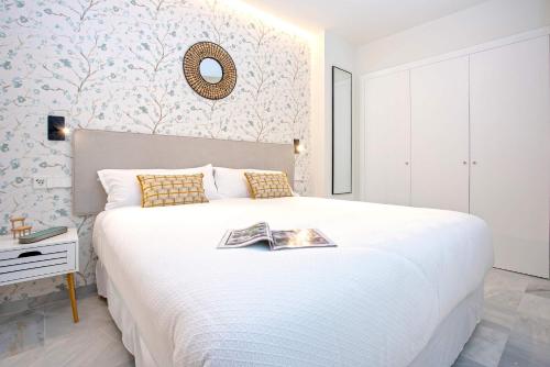 a bedroom with a large white bed and a mirror at Genteel Home Catedral in Cádiz