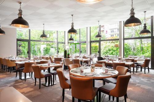 a restaurant with tables and chairs and large windows at Residhome Paris-Evry in Evry-Courcouronnes