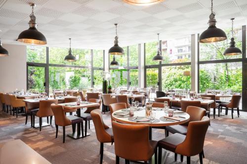 een restaurant met tafels en stoelen en grote ramen bij Residhome Paris-Evry in Courcouronnes