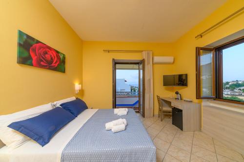 a bedroom with a bed and a desk with a red rose at La Rosa - Luxury B&B in Ischia