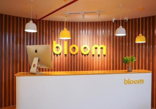 a reception desk with a yellow bloom sign on a wall at Bloom Hotel Koregaon Park in Pune