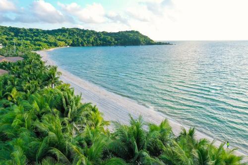 an aerial view of a beach with trees and water at La Grotta Hotel - Phu Quoc Emerald Bay in Phu Quoc