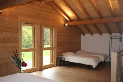 two beds in a wooden room with a window at Chalet au cœur des bois in Larringes