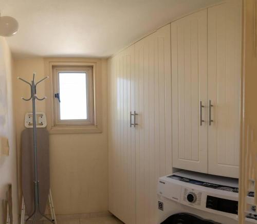 uma cozinha com armários brancos e uma janela em Captivating Lake & Oceanview Getaway House em Meneou