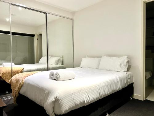 a bedroom with two beds and a mirror at ReadySet Apartments on Little Collins in Melbourne