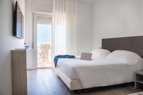 a bedroom with a white bed with a laptop on it at Hotel Villa Sorriso in Lido di Jesolo