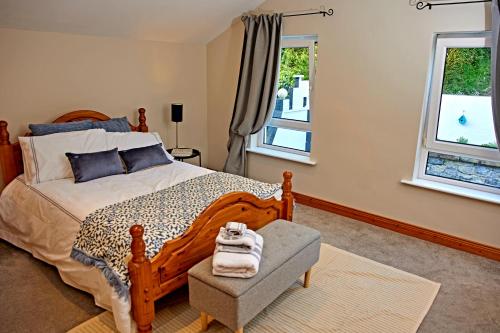 a bedroom with a bed and a chair and two windows at 'Maigue View' by the River in Croom