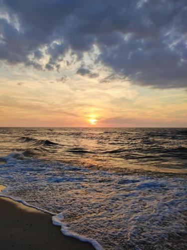a sunset on the beach with the ocean at Domki Płyniewoda - całoroczne domy PREMIUM, klimatyzacja, kominek, blisko morza in Dziwnów
