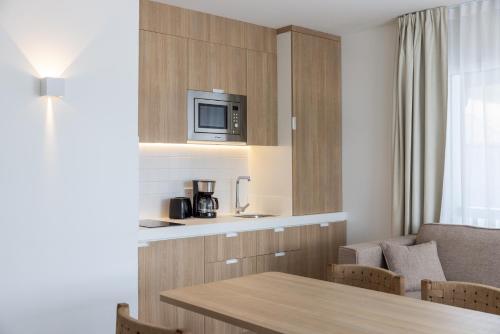 a kitchen with a table and a microwave above it at Résidence Ibaïa - Piscine & Spa in Hendaye