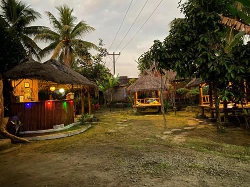 a group of huts with palm trees and a building at MATRAHAYA BUNGALOWS in Tetebatu