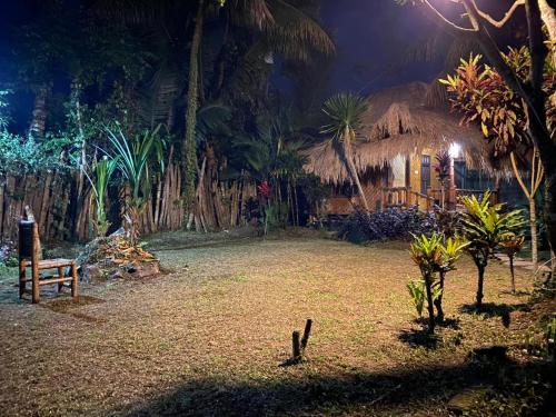 a house with a thatch roof in a yard at night at MATRAHAYA BUNGALOWS in Tetebatu