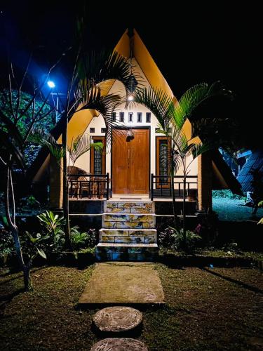 a house with a wooden door and some palm trees at MATRAHAYA BUNGALOWS in Tetebatu