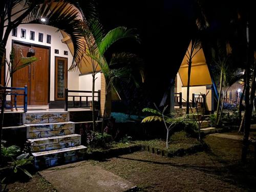 a house with a wooden door and some palm trees at MATRAHAYA BUNGALOWS in Tetebatu