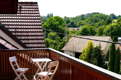 two chairs and a table on a wooden balcony at Penzion Pod Ždánovem in Nezdice