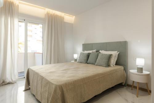 um quarto branco com uma cama grande e uma janela em Miral 5 Sea front by HD Properties em Quarteira