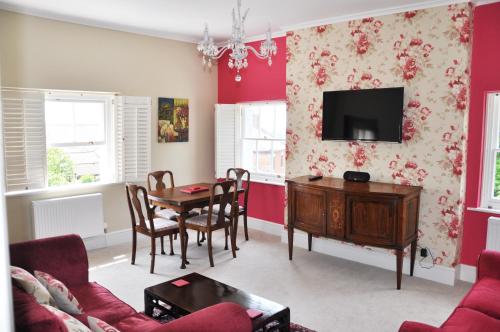 a living room with a table and a tv at Bove Town House Apartments in Glastonbury