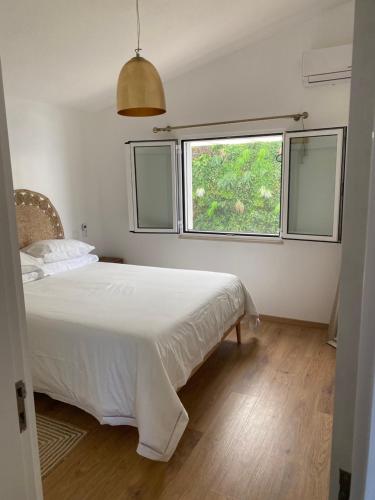 een slaapkamer met een wit bed en een raam bij Villacielgacha in São Brás de Alportel