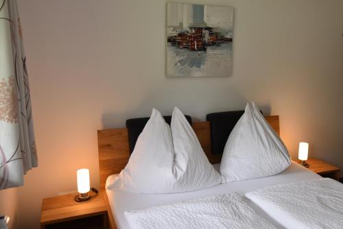 a white bed with white pillows and two candles at Sunseitn Apartments in Gosau