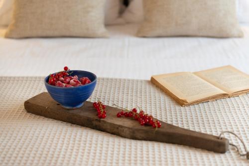 a bowl of berries and a book on a bed at CeraMio Suites in Limenas