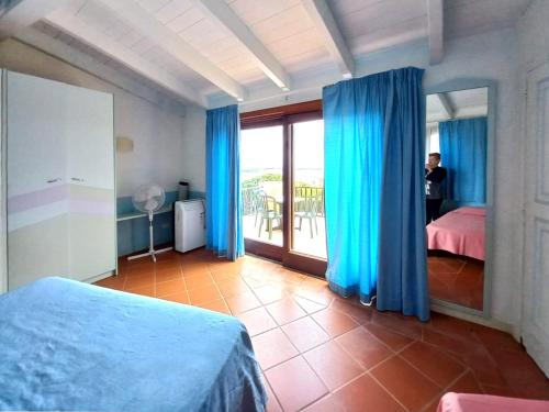 una camera da letto con tende blu, un letto e un balcone di Villa La Rocca a Stintino